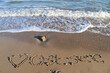 The german word Ostsee (Baltic Sea) and a heart written into the sand of the beach.