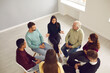 Top view people of different ages and nationalities sit close to each other in a circle and communicate with each other. People communicate with a friendly psychologist. Group therapy concept.