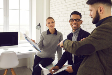 Brainstorming, multiethnic business group team, cooperation concept. Young smiling african american and caucasian business partners sitting in modern office and discussing corporate tasks