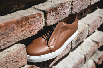 Brown sneakers or shoes with white sole, close up. Bricks background