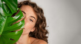 Fototapeta  - Beautiful woman with natural make up and green leaves