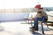 © Cavan Images - Young hooded boy sitting on a bench with shoes over skateboard