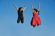 © Cavan Images - Young women couple smiling and jumping with blue sky in the background. summer concept
