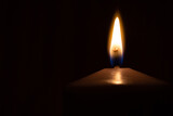 Fototapeta  - Burning wax candle in the darkness with copy space. Symbol for hope, memorial, romance.