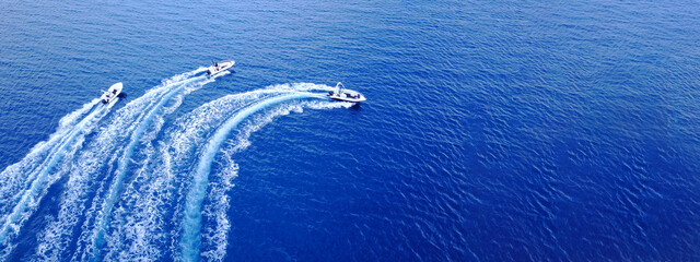 Wall Mural - Aerial drone ultra wide top down photo of synchronised powerboats cruising in high speed in deep blue open ocean sea