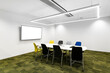Mała sala konferencyjna w korporacji z monitorem na ścianie, krzesłami, stołem oraz zieloną podłogą