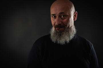 Wall Mural - close up photo, portrait of a serious, thoughtful, bearded man on a dark background confident and dramatic looking straight. Concept of male portrait.  Low key 