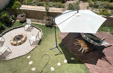 Average Australian back yard with umbrella fire pit deck relaxing dog hot summer day