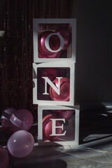 Canvas Print - Vertical shot of transparent containers with balloons stack on each other forming the word one