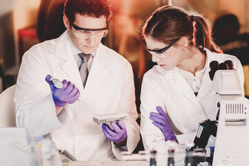 Poster - Life scientist researching in laboratory. Focused life science professionals pipetting master mix solution into the PCR 96 well micro plate using multi channel pipette. Healthcare and biotechnology.