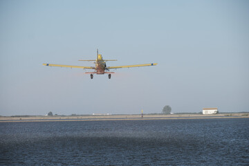 Single-engine propeller airplane flying in a perfectly clear blue sky over a farm  landscape