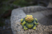Selective Focus Shot Of A Green Garden Figure Of A Frog On A Stone Wall