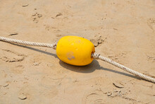 Close-up Of Yellow Buoy With Rope On Sand