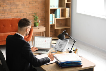 Wall Mural - Businessman trying to meet deadline in office