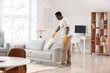 © Pixel-Shot - African-American man cleaning his flat