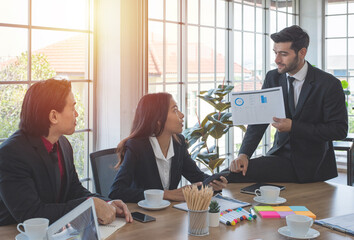 Caucasian businessman show presentation chart to Asian co-worker at working place in meeting room.