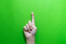 Cropped Hand Of Child Gesturing Against Green Background