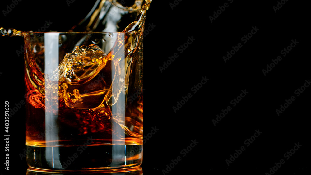 Ice Cube falling into Glass of Whisky, Freeze Motion. - obrazy, fototapety, plakaty 