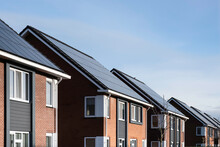 Solar Panels Mounted On The Roofs Of A Row Modern New-build Houses In Lemmer, Friesland, The Netherlands With Blue Sky