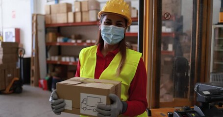 Sticker - Mature woman with package in hands work inside delivery warehouse while wearing safety mask for coronavirus 