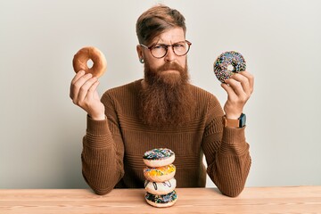 Sticker - Young irish redhead man eating doughnut for breakfast skeptic and nervous, frowning upset because of problem. negative person.