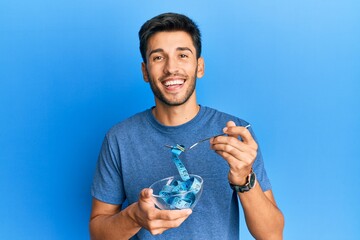 Young handsome man eating measure meter doing diet for weight loss smiling and laughing hard out loud because funny crazy joke.