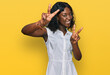 © Krakenimages.com - Beautiful african young woman wearing casual clothes smiling looking to the camera showing fingers doing victory sign. number two.