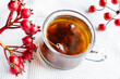 Fruit tea made from berries and rosehip fruits in a transparent glass mug. Hot drink like fresh compote on a white towel