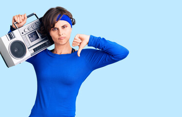 Sticker - Beautiful young woman with short hair wearing workout clothes and holding boombox with angry face, negative sign showing dislike with thumbs down, rejection concept