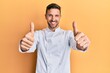 © Krakenimages.com - Handsome man with beard wearing professional cook uniform approving doing positive gesture with hand, thumbs up smiling and happy for success. winner gesture.