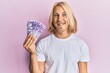 © Krakenimages.com - Caucasian young man with long hair holding 100 philippine peso banknotes looking positive and happy standing and smiling with a confident smile showing teeth
