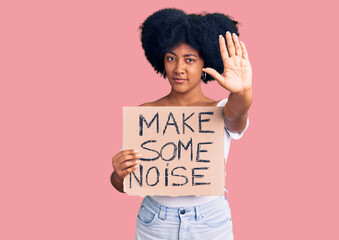 Wall Mural - Young african american girl holding make some noise banner with open hand doing stop sign with serious and confident expression, defense gesture