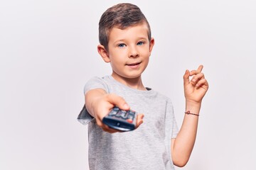 Wall Mural - Cute blond kid holding television remote control smiling happy pointing with hand and finger to the side