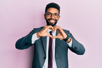 Canvas Print - Handsome hispanic business man with beard wearing business suit and tie smiling in love doing heart symbol shape with hands. romantic concept.