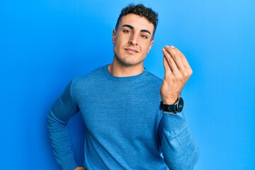 Hispanic young man wearing casual winter sweater doing italian gesture with hand and fingers confident expression