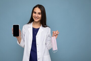 Photo of beautiful smiling young woman good looking wearing casual stylish outfit standing isolated on background with copy space holding smartphone showing phone in hand with empty screen display for