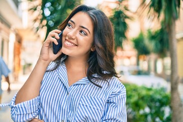 Young hispanic businesswoman smiling happy talking on the smartphone at the city.