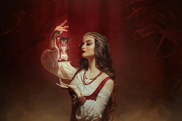 Fantasy woman creates magic. Gypsy girl witch holding magical hourglass in hands. Photo levitation. Time control youth concept. Spiritual lady looks, reads future. Fairy tale Image of Fortune Teller