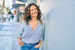 © Krakenimages.com - Middle age hispanic woman smiling happy leaning on the wall at the city.