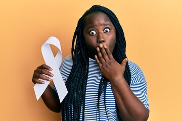 Poster - Young black woman with braids holding white ribbon covering mouth with hand, shocked and afraid for mistake. surprised expression