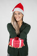 © MrsLePew - beautiful young woman wearing a santa hat presenting a  red Christmas gift