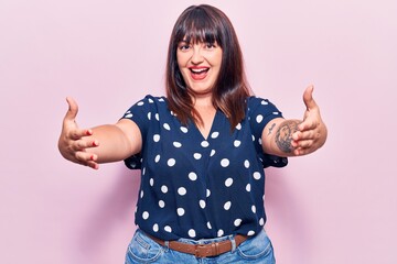 Poster - Young plus size woman wearing casual clothes looking at the camera smiling with open arms for hug. cheerful expression embracing happiness.