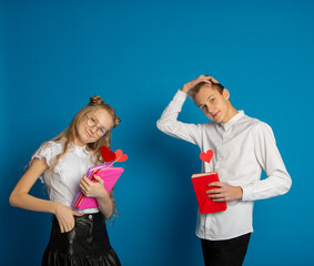 A couple of schoolchildren are teenagers on Valentine's Day on a blue background