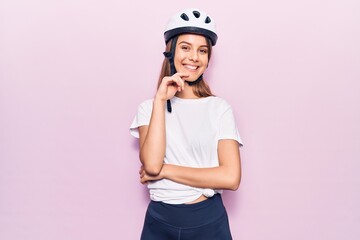 Wall Mural - Young beautiful girl wearing bike helmet smiling looking confident at the camera with crossed arms and hand on chin. thinking positive.