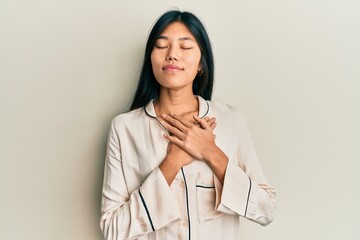 Sticker - Young chinese woman wearing pajama smiling with hands on chest with closed eyes and grateful gesture on face. health concept.