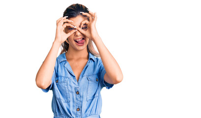 Sticker - Young beautiful woman wearing casual clothes doing ok gesture like binoculars sticking tongue out, eyes looking through fingers. crazy expression.