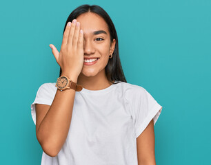 Wall Mural - Young asian woman wearing casual white t shirt covering one eye with hand, confident smile on face and surprise emotion.
