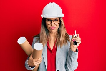 Sticker - Beautiful brunette woman wearing safety helmet holding blueprints skeptic and nervous, frowning upset because of problem. negative person.