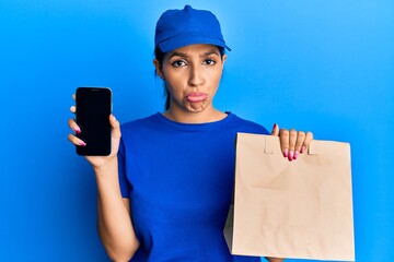 Sticker - Beautiful brunette woman holding delivery paper bag and showing smartphone screen depressed and worry for distress, crying angry and afraid. sad expression.