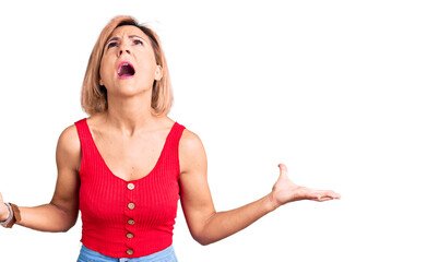 Poster - Young blonde woman wearing casual clothes crazy and mad shouting and yelling with aggressive expression and arms raised. frustration concept.